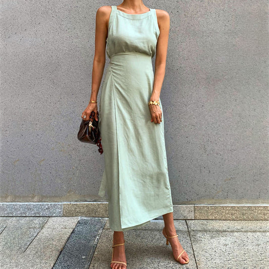 Woman wearing a light green sleeveless dress against a gray wall.